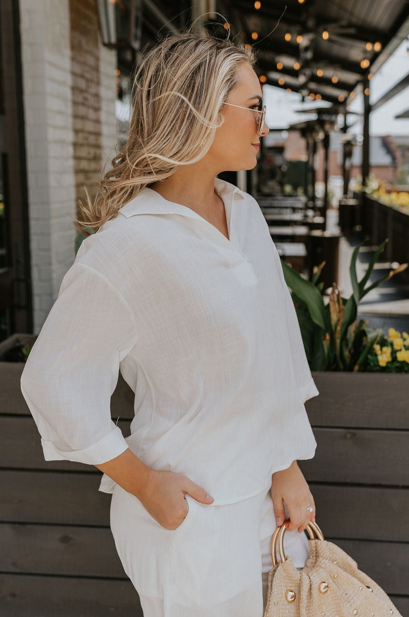Side view of female model wearing the Rebecca Ivory Linen Top which features vory Linen Fabric, Half Sleeves and Collared Neckline with V-Cutout
