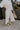 Side view of female model wearing the Rebecca Ivory Linen Cropped Pants which features Ivory Linen Fabric, Cropped Pant Legs, Ivory Lining, Two Side Pockets and Elastic Waistband
