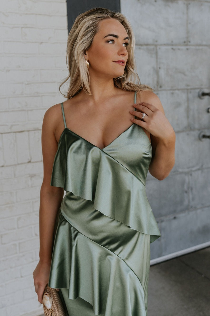Front view of female model wearing the Azalea Dark Sage Satin Ruffle Midi Dress which features Green satin fabric Diagonal ruffles down the bust and waist, Spaghetti straps, V-Neckline, Elastic across the back top and Midi length
