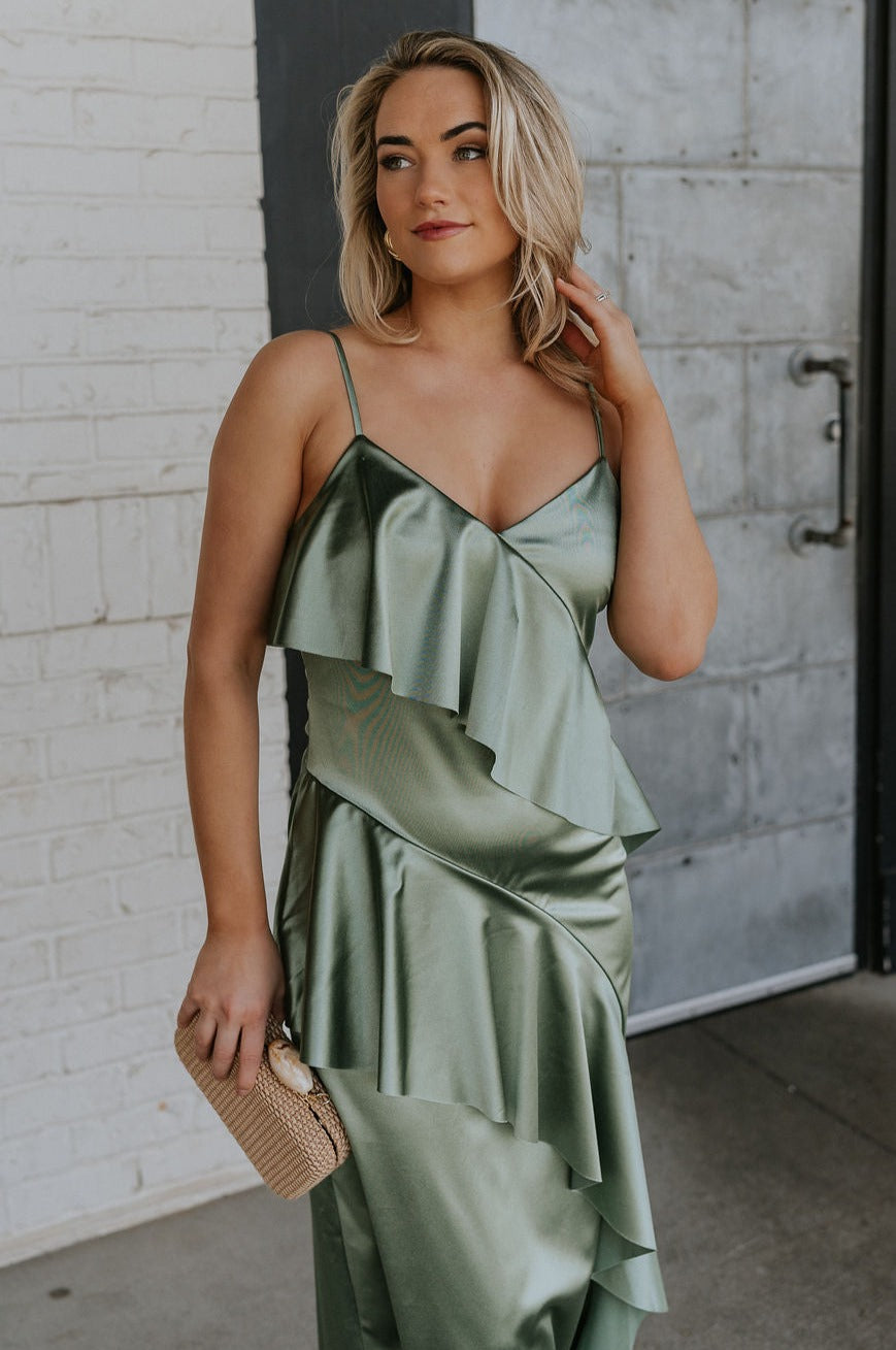 Front view of female model wearing the Azalea Dark Sage Satin Ruffle Midi Dress which features Green satin fabric Diagonal ruffles down the bust and waist, Spaghetti straps, V-Neckline, Elastic across the back top and Midi length