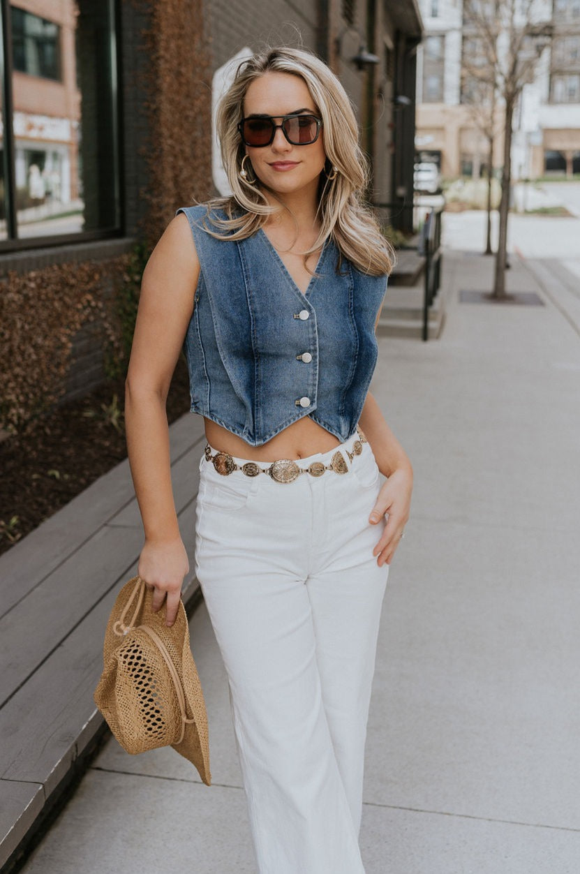 Full body view of female model wearing the Brynn Medium Denim Button-Up Vest which features Medium Denim Wash Fabric, Button-Up Front Closure, Cropped Waist, V-Neckline and Sleeveless