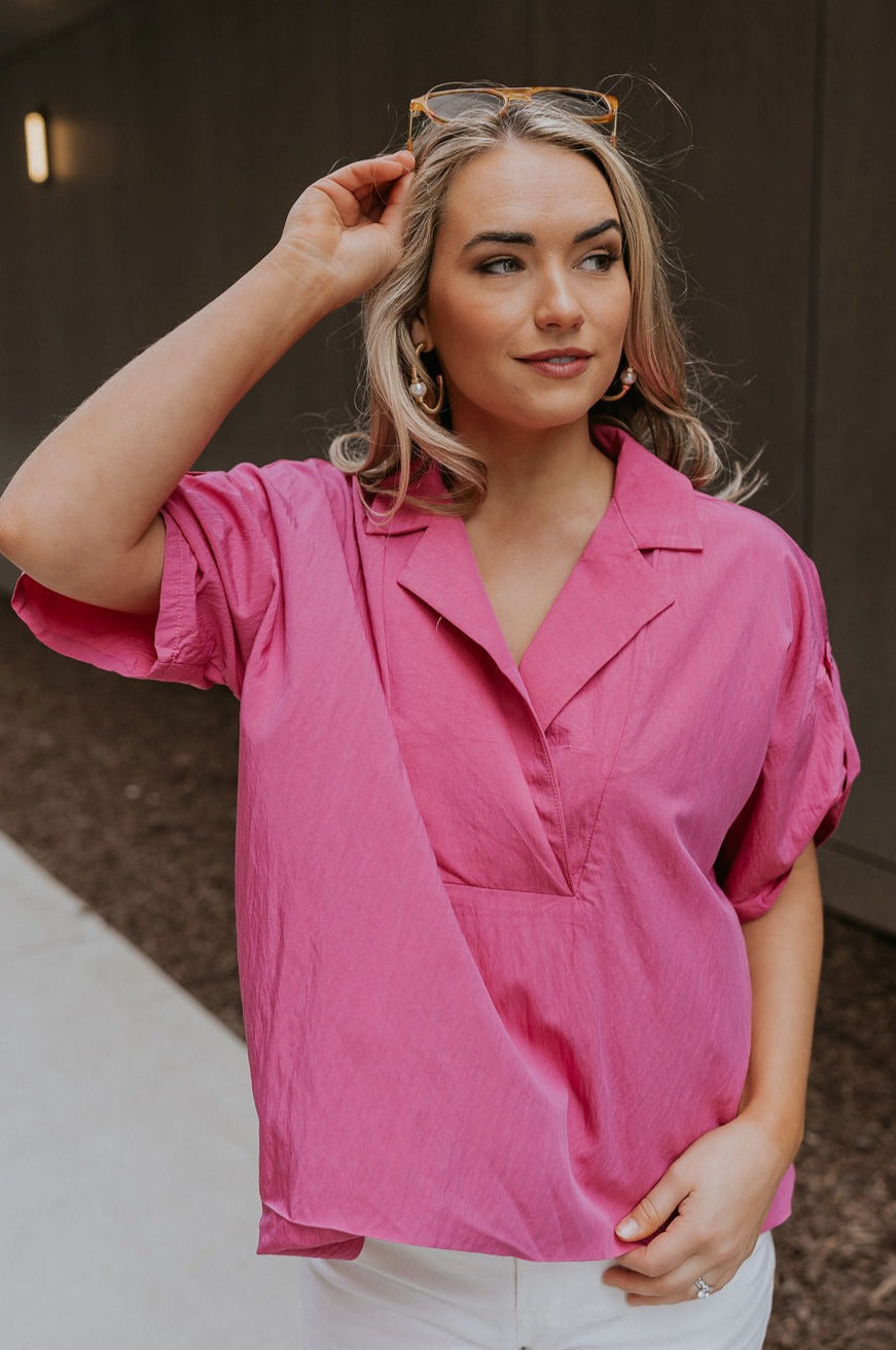Front view of female model wearing the Everlee Pink Short Sleeve Top which features Pink Lightweight Fabric, Short Sleeves with Pearlescent Buttoned Cuffs and Collar Neckline with V-Cutout