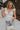 Front view of female model wearing the Lauren White Ruffle Plunge Neckline Tank which features White Lightweight Fabric, Peplum Hem Body, Sweetheart Neckline, Ruffle Straps, Open Back Corset Tie and Back Zipper with Hook Closure