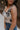 Close up side view of female model wearing the Elaina Black & Cream Floral Tank which features Black and Cream Floral Smocked Fabric, Cropped Waist, Lettuce Hem Details, Square Neckline and Thick Straps