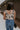 Back view of female model wearing the Elaina Black & Cream Floral Tank which features Black and Cream Floral Smocked Fabric, Cropped Waist, Lettuce Hem Details, Square Neckline and Thick Straps