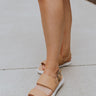 Frontal side view of female model wearing the ONA Streetworks Go-To Flat Sandal in Honest Beige & Sea Salt which features Beige Leather Upper, Adjustable Buckle Closure with Back Strap, White Molded Rubber Sole and 1" Platform Height