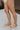 Side view of female model wearing the ONA Streetworks Go-To Flat Sandal in Honest Beige & Sea Salt which features Beige Leather Upper, Adjustable Buckle Closure with Back Strap, White Molded Rubber Sole and 1" Platform Height