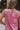 Clos eup back view of female model wearing the Rowan Pink Sleeveless Jumpsuit which features Pink Satin Fabric, Wide Pant Legs, Round Neckline, Sleeveless and Back Key Hole with Button Closure