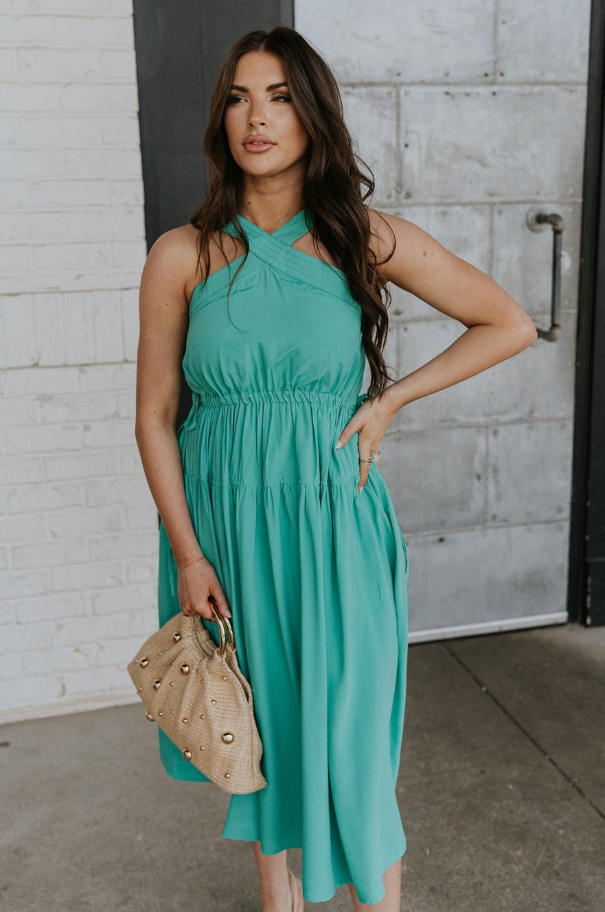 Front view of female model wearing the Vera Halter Cross Neckline Midi Dress in Green which features Lightweight Fabric, Lining, Midi Length, Side Ties Waistband, Halter Cross Neckline, Adjustable Straps and Sleeveless.