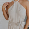 Close up view of female model wearing the Lilah Natural Linen Halter Neckline Jumpsuit which features Natural Linen Fabric, Wide Pant Legs, Tie Waistband, Twist Halter Neckline with Button Closure and Back Key Hole Design
