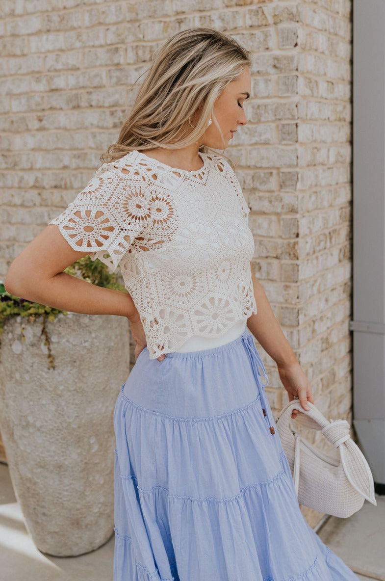 Side view of female model wearing the Brynlee Cream Crochet Scallop Top which features Cream Crochet Fabric, Cropped Waist, Round Neckline and Short Sleeves