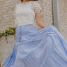 Full body view of female model wearing the Alana Periwinkle Tiered Maxi Skirt which features Periwinkle Lightweight Fabric, Maxi Length, Periwinkle Thigh Length Lining, Tiered Body and Elastic Waistband with Drawstring Ties