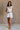 Full body view of female model wearing the Kassidy White Denim Sleeveless Romper which features White Cotton Fabric, Two Front Pockets, Two Back Pockets, Fray Hem, Adjustable Tie Straps and Sleeveless