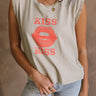 Close up view of female model wearing the Kiss Stone Taupe Graphic Top which features Stone Taupe Cotton Fabric, Distressed Details, Sleeveless, Round Neckline and Kiss Graphic with Lips