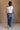 Full body back view of model wearing the Oakley White Sleeveless Top which features light blue knit fabic, cropped waist, scooped neckline, thick straps and sleeveless.