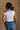 Back view of model wearing the Oakley White Sleeveless Top which features light blue knit fabic, cropped waist, scooped neckline, thick straps and sleeveless.