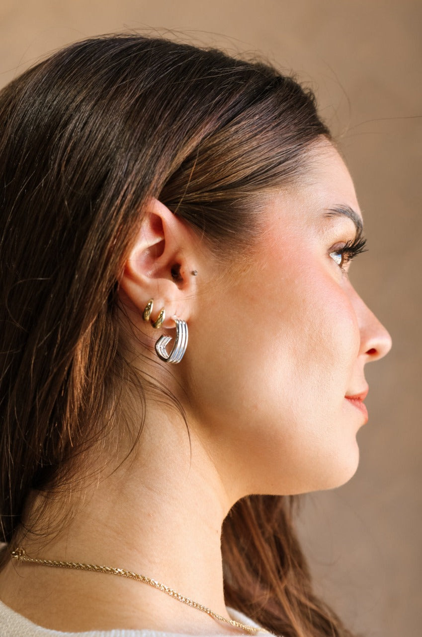 Side view of model's face; model is wearing the Amalia Silver Layered Hoop Earring that feature angular layered silver hoops