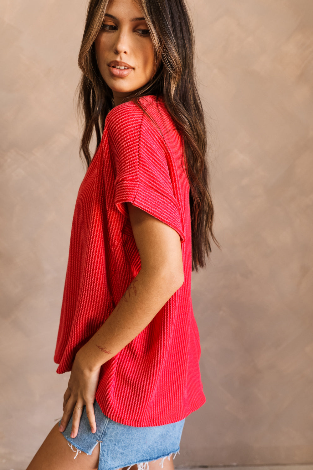 Side view of model wearing the Destiny Ribbed Short Sleeve Top in Red which features Ribbed Fabric, Round Neckline and Short Sleeves.