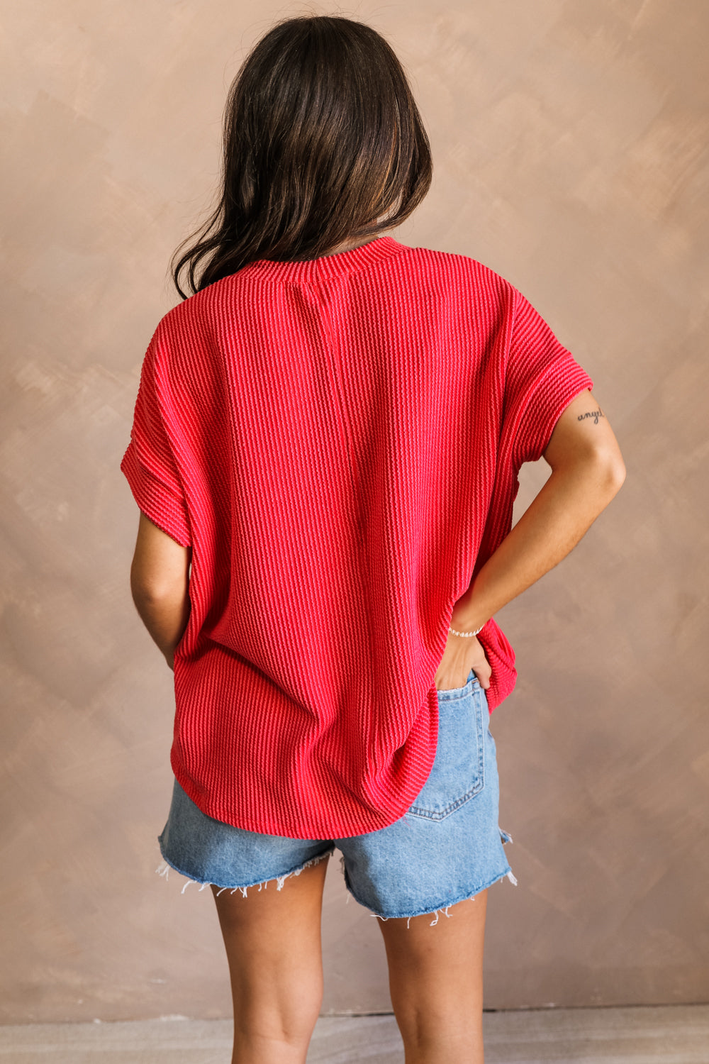 Back view of model wearing the Destiny Ribbed Short Sleeve Top in Red which features Ribbed Fabric, Round Neckline and Short Sleeves.