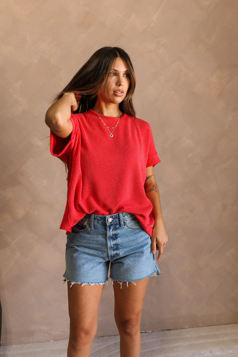 Full body front view of model wearing the Destiny Ribbed Short Sleeve Top in Red which features Ribbed Fabric, Round Neckline and Short Sleeves. Top is front tucked