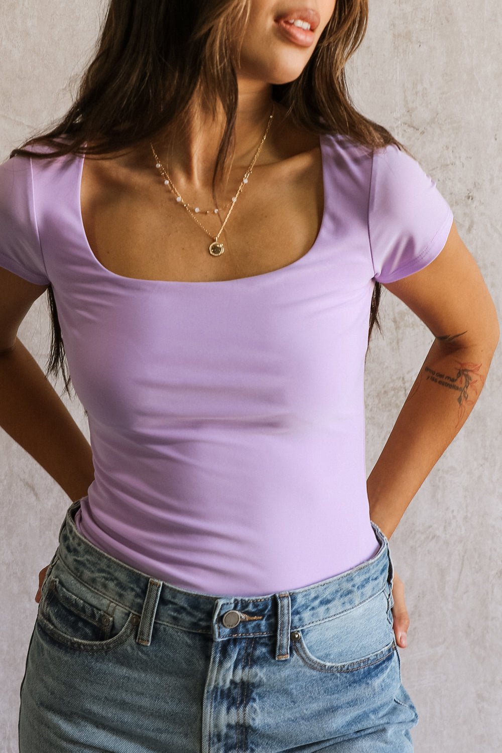 Close-up front view of female model wearing the Dani Lavender Short Sleeve Top that has stretchy lavender fabric, a square neck, and short sleeves.