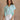 Upper body front view of female model wearing the Amalia Collared Short Sleeve Top in mint, which has short sleeves and a collar neckline. Paired with white capris. Model is holding white purse. Top is front tucked
