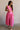 Full body view of female model wearing the Valery Pink Cropped Tank which features Pink Cotton Fabric,  Cropped Waist, Upper Pleated Details, V-Neckline,  Sleeveless and Back Tie Closure with Light Wood Beads 