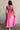 Full body back view of female model wearing the Valery Pink Cropped Tank which features Pink Cotton Fabric, Cropped Waist, Upper Pleated Details, V-Neckline, Sleeveless and Back Tie Closure with Light Wood Beads