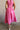 Back view of female model wearing the Valery Pink Tiered Midi Skirt which features Pink Cotton Fabric, Pink Lining, Upper Pleated Details and Smocked Waistband
