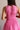 Back view of female model wearing the Valery Pink Cropped Tank which features Pink Cotton Fabric, Cropped Waist, Upper Pleated Details, V-Neckline, Sleeveless and Back Tie Closure with Light Wood Beads