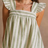 Close front view of female model wearing the Coraline that has green and ivory stripes, ruffled straps, and a cropped babydoll fit. 
