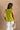 Back view of female model wearing the Marceline Chartreuse Ruffled Top that has bright chartreuse green fabric, ruffled sleeve trim, and a v neck.
