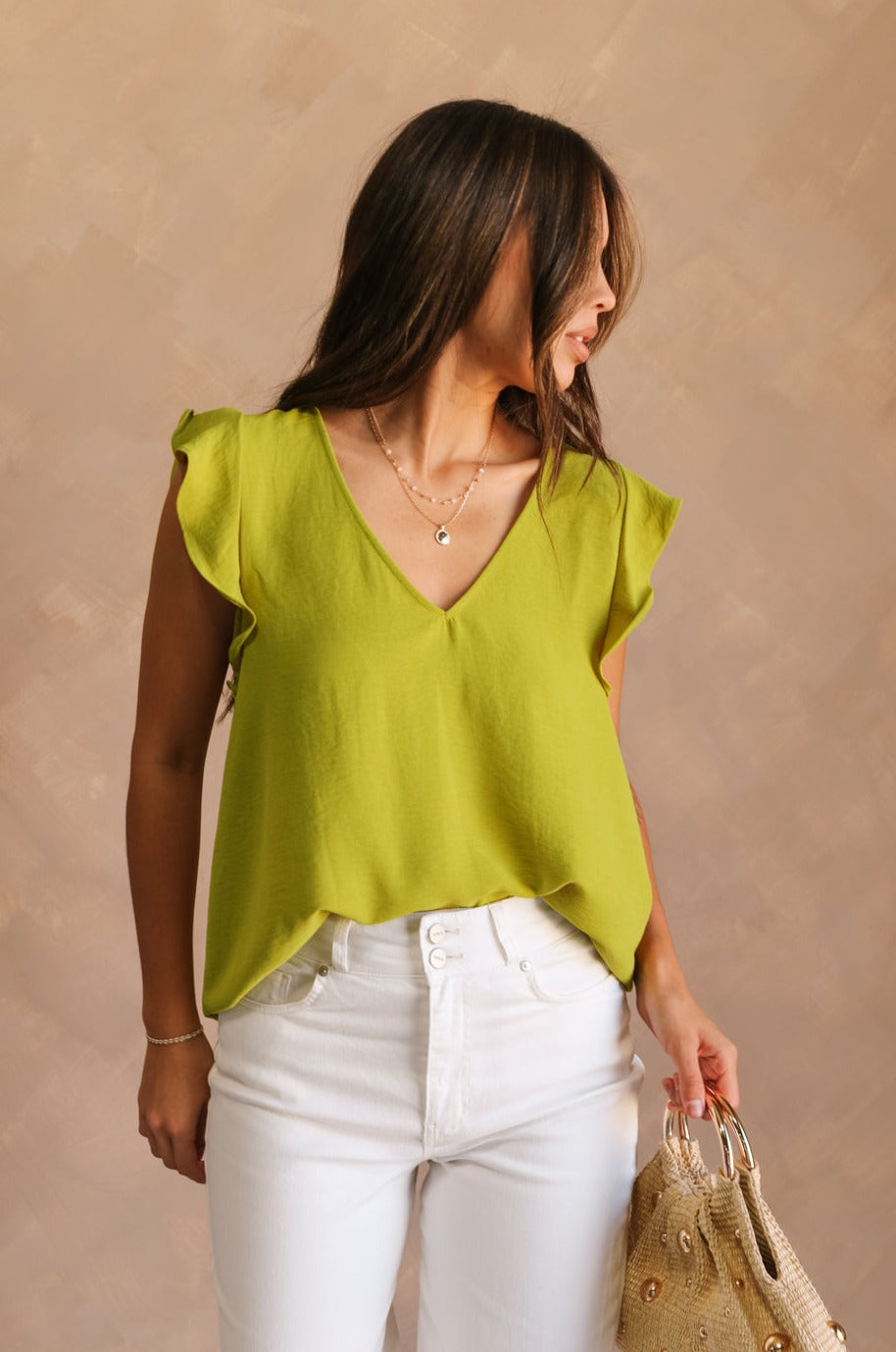 Front view of female model wearing the Marceline Chartreuse Ruffled Top that has bright chartreuse green fabric, ruffled sleeve trim, and a v neck. Top is front tucked.