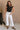 Full body view of female model wearing the Cienna Cream Cropped Wide Leg Pants which features White Cotton Slight Stretch Fabric, Cropped Wide Pant Legs, Thick Hem Detail, Two Front Pockets, Two Back Pockets, Front Zipper with Double Button Closure and Belt Loops