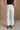 Back view of female model wearing the Cienna Cream Cropped Wide Leg Pants which features White Cotton Slight Stretch Fabric, Cropped Wide Pant Legs, Thick Hem Detail, Two Front Pockets, Two Back Pockets, Front Zipper with Double Button Closure and Belt Loops