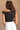 Back view of model wearing the Oakley White Sleeveless Top which features black fabric, cropped waist, scooped neckline, thick straps and sleeveless.