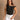 Close-up front view of model wearing the Oakley White Sleeveless Top which features black fabric, cropped waist, scooped neckline, thick straps and sleeveless.
