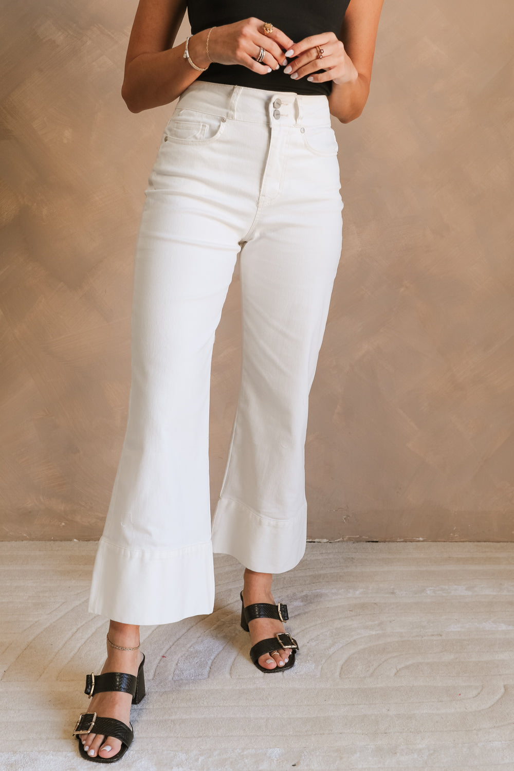 Front view of female model wearing the Cienna Cream Cropped Wide Leg Pants which features White Cotton Slight Stretch Fabric, Cropped Wide Pant Legs, Thick Hem Detail, Two Front Pockets, Two Back Pockets, Front Zipper with Double Button Closure and Belt Loops