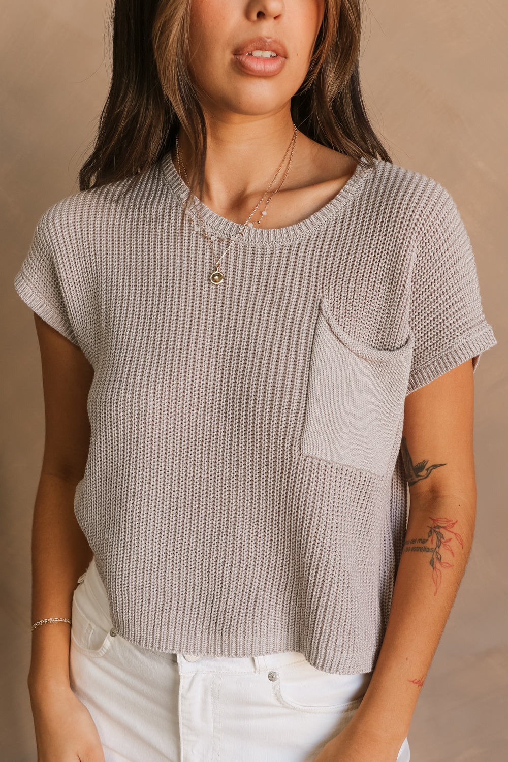Close up view of female model wearing the Harper Grey Knit Short Sleeve Top which features Grey Small Cable Knit Fabric, Left Front Chest Pocket, Round Neckline and Short Sleeves