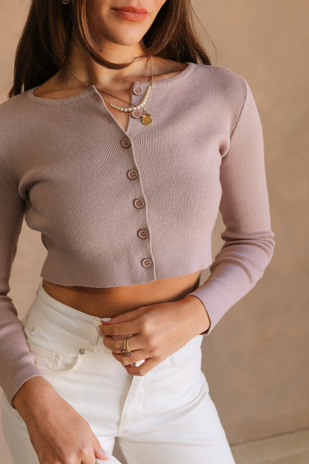 Close up view of female model wearing the Avery Lilac Button-Up Cropped Cardigan which features Lilac Cotton Knit Fabric, Cropped Waist, Monochrome Front Button Up Closure and Long Sleeves