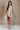 Full body view of female model wearing the Elodie Beige Ruffle Tier Sleeveless Romper which features Beige Lightweight Fabric, Beige Lining, Ruffle Tier Details, Round Neckline, Sleeveless and Back Button Closure