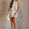 Full body view of female model wearing the Elodie Beige Ruffle Tier Sleeveless Romper which features Beige Lightweight Fabric, Beige Lining, Ruffle Tier Details, Round Neckline, Sleeveless and Back Button Closure
