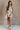 Full body view of female model wearing the Elodie Beige Ruffle Tier Sleeveless Romper which features Beige Lightweight Fabric, Beige Lining, Ruffle Tier Details, Round Neckline, Sleeveless and Back Button Closure