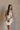 Front view of female model wearing the Elodie Beige Ruffle Tier Sleeveless Romper which features Beige Lightweight Fabric, Beige Lining, Ruffle Tier Details, Round Neckline, Sleeveless and Back Button Closure