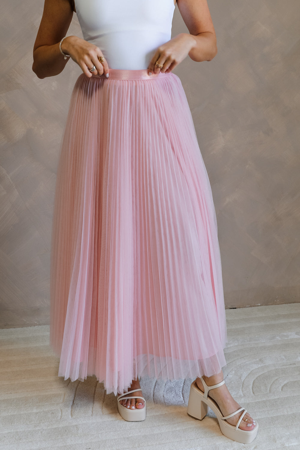 Front view of female model wearing the Adele Dusty Pink Pleated Tulle Midi Skirt which features Dusty Pink Tulle Pleated Fabric, Dusty Pink Lining, Midi Length and Satin Elastic Band