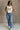 Full body view of female model wearing the Free Bird Smoke Cropped Tank which features Cream Cotton Fabric, Cropped Lettuce Hem, Round Neckline, Sleeveless and Eagle Graphic 