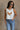 Front view of female model wearing the Free Bird Smoke Cropped Tank which features Cream Cotton Fabric, Cropped Lettuce Hem, Round Neckline, Sleeveless and Eagle Graphic