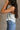 Side view of female model wearing the Free Bird Smoke Cropped Tank which features Cream Cotton Fabric, Cropped Lettuce Hem, Round Neckline, Sleeveless and Eagle Graphic