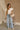 Full body front view of female model wearing the Jemma White Ruffle Top that has white fabric, short ruffled cap sleeves, a v neckline, and keyhole back. Worn with blue jeans.