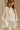 Front view of female model wearing the Kimberly Cream Pleated Long Sleeve Top which features Cream Sheer Plisse Fabric, Cropped Waist, Lettuce Hem Details, Round Neckline and Open Back with Tie Closures